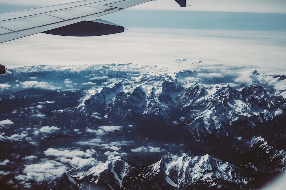 Blick aus dem Flugzeug auf schneebedeckte Berge