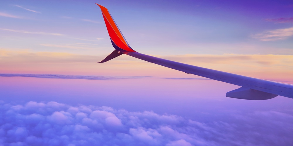 Die rechte Tragefläche eines Flugzeuges im Wolkenhimmel