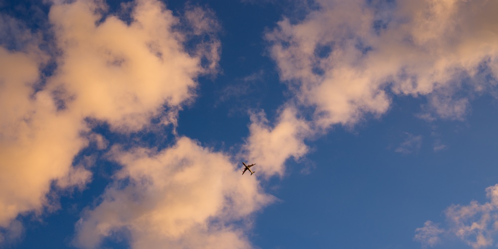 Ein Flugzeug von unten mit Wolken und blauen Himmel