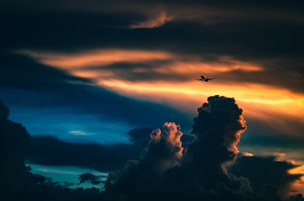 Imposanter Wolkenhimmel mit beleuchtetem Flugzeug